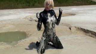 Super Hot Blond Girl in Black Latex Catsuit + High Heels and Sunglasses Bathes in the Mud - Mud Bath