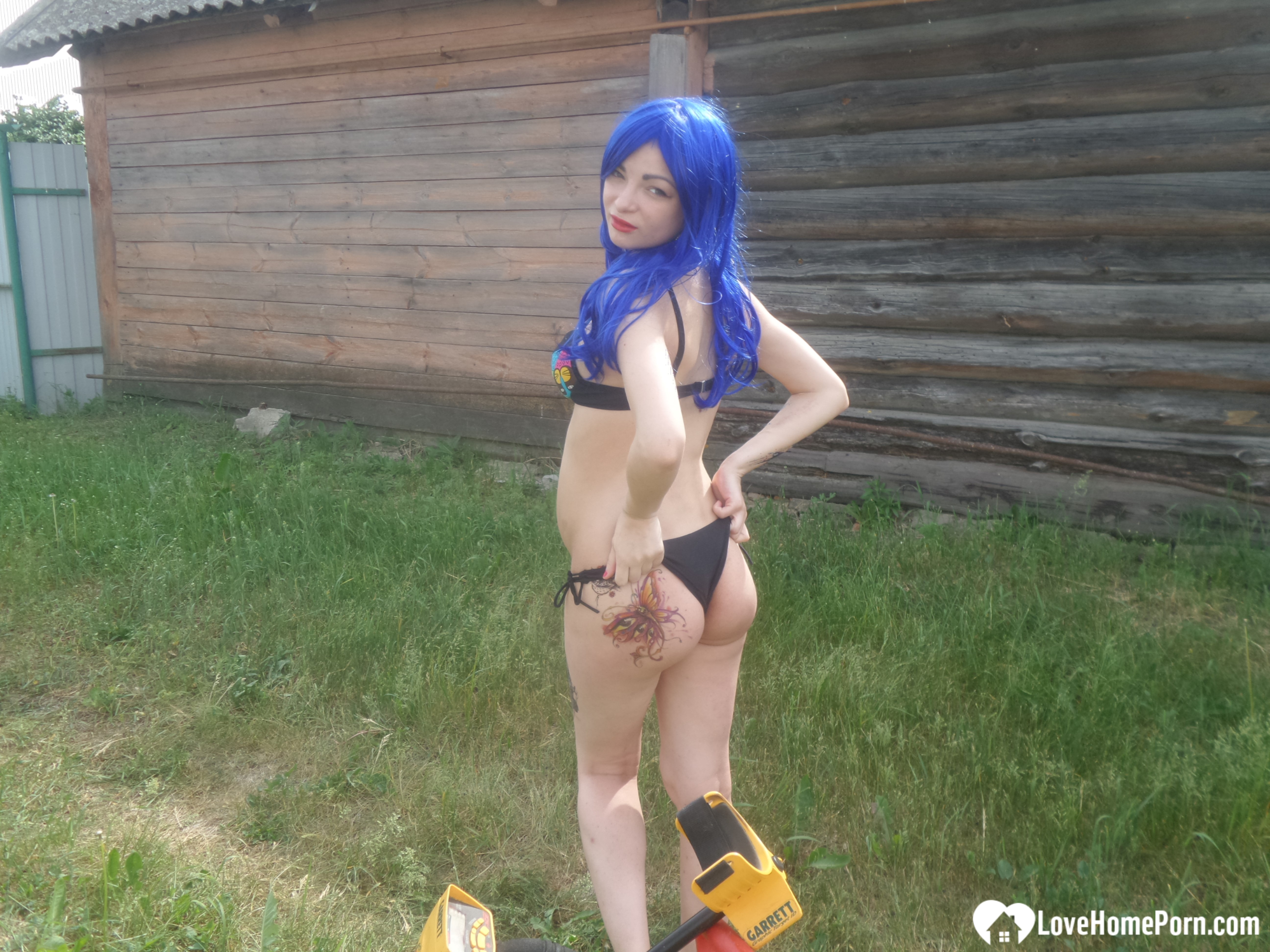 Blue-haired beauty showing her bust while gardening